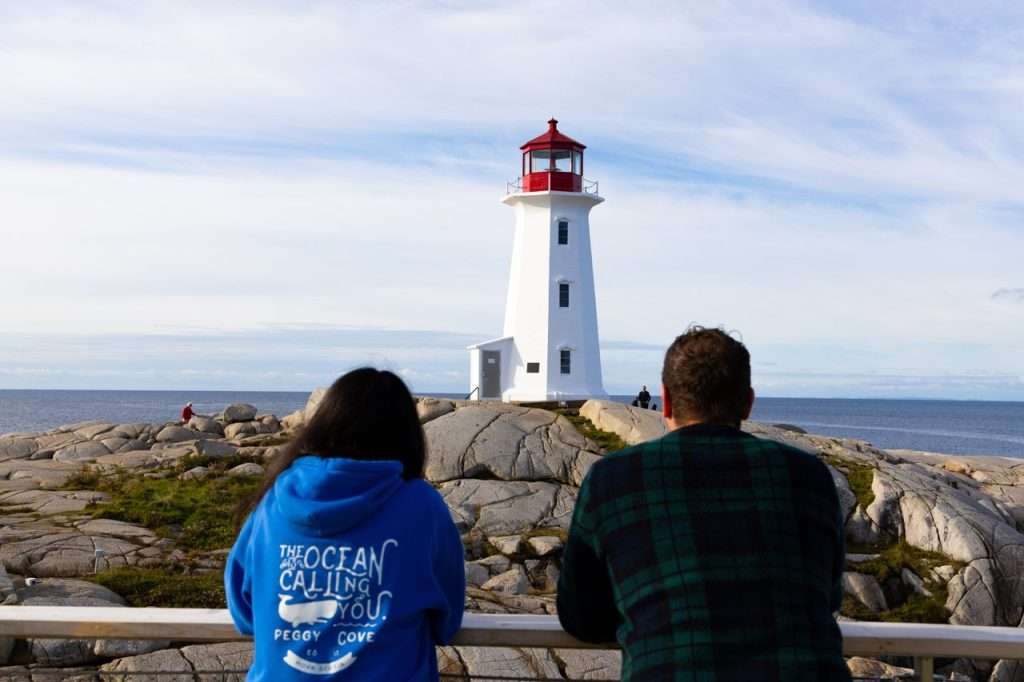 A couple admiring the Peggy's Cove Lighthouse.