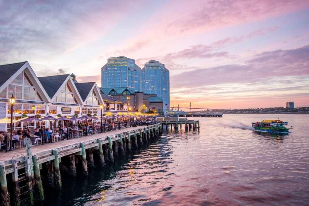 Halifax waterfront boardwalk with restaurants, ferry, and harbour at sunset