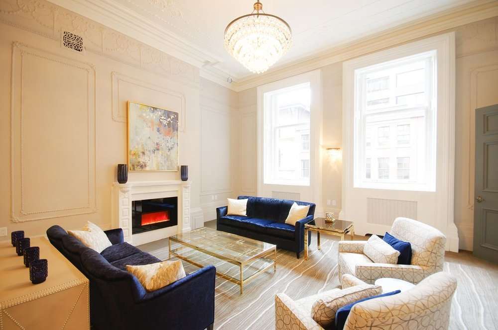 Elegant lounge at Cameo Hotel in Halifax, Nova Scotia, with navy sofas, cream armchairs, a fireplace and chandelier.